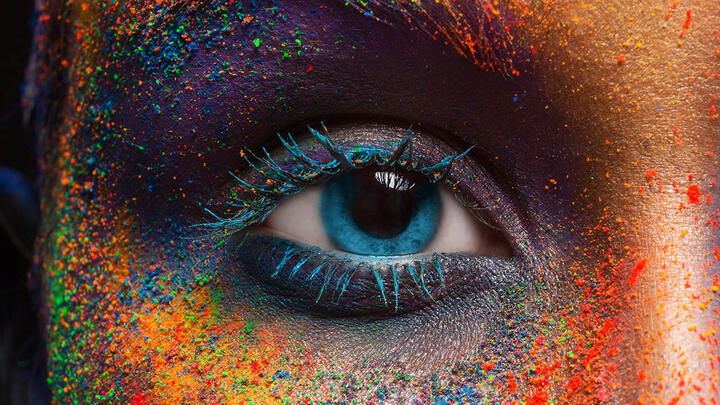 A closeup of a womans eye with colorful eyeshadow scattered all over